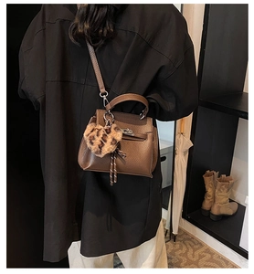 Détail du sac en cuir marron avec boucle métallique et pendentif cœur léopard