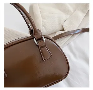 Close-up of shiny brown patent leather bag with silver metal rings and stitching
