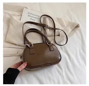 Detail of a brown polished leather Boston bag featuring silver hardware and a top handle