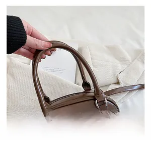 Detail of a deep brown faux leather handbag showing silver hardware and smooth handles