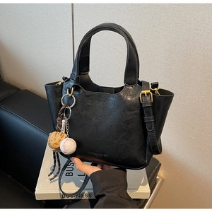 Détail du sac seau noir en simili cuir avec breloque baseball et fermeture magnétique