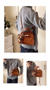 Détail du sac Kelly en cuir marron à motif litchi avec boucle argentée et breloque léopard
