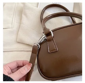Close-up of vintage brown crossbody bag featuring silver metal hook and sleek handle