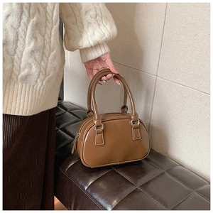 Detail of vintage brown semi-oval leather handbag with silver metallic rings and smooth finish