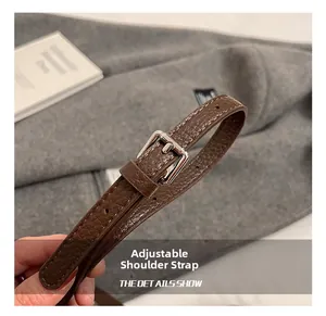 Dettaglio della tracolla regolabile in pelle marrone con fibbia in metallo argento