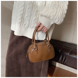 Close-up of a brown bowling handbag with double top handles and silver hardware