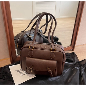 Detalle de bolso vintage de cuero marrón oscuro con hebillas doradas retro y dos asas