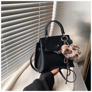 Détail du sac Kelly noir à grain de litchi avec breloque pompon léopard et fermoir