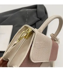 Detail of contrast color handbag featuring snake pattern texture and gold metal hardware