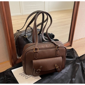 Detalle de bolso mensajero vintage marrón de cuero PU con hebillas metálicas sobre fondo seda