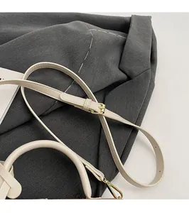 Detail of adjustable shoulder strap and golden metal buckle on beige leather handbag