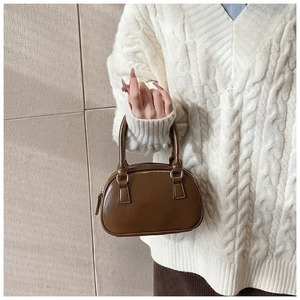 Detail of dark brown PU leather bowling bag with round handles and silver hardware