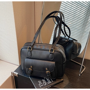 Close-up of black vintage PU leather messenger bag with gold buckles and front pocket