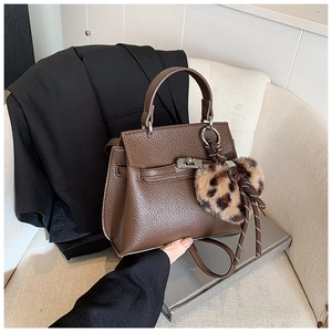 Détails du sac à main en cuir marron foncé avec fermoir argenté et pompon léopard chic