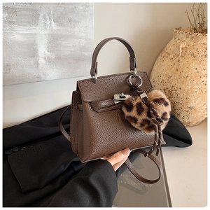 Détail du sac Kelly marron foncé avec fermoir métallique et breloque cœur léopard