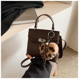 Détail du sac à main en cuir marron foncé avec fermoir argenté et breloque cœur léopard