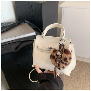 Gros plan du sac à main en cuir blanc avec breloque cœur léopard et fermoir argenté