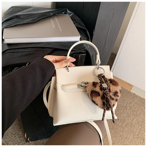 Gros plan du sac en cuir blanc avec breloque cœur léopard et finitions argentées