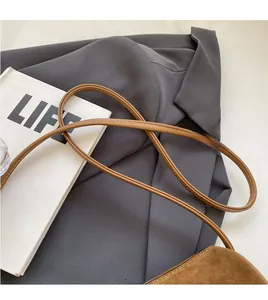 Detail of vintage brown suede Boston bag with slim leather strap on stylish blazer