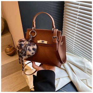 Détail du sac à main en cuir marron avec fermoir argenté et breloque cœur léopard