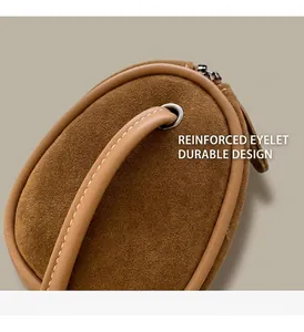 Detail of metal grommets and stitching on a brown suede cylinder crossbody bag handle