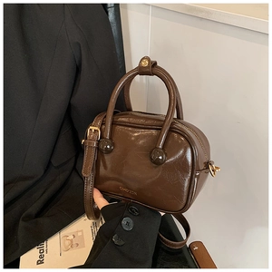 Dettaglio della borsa a cuscino marrone scuro lucida con logo CIHO'2DN e hardware dorato