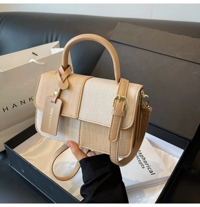 Detail einer beige gewebten Mini-Umhängetasche mit Ledergriff in einer Geschenkbox