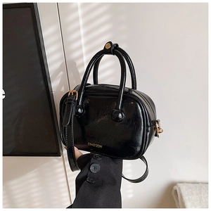 Dettaglio della piccola borsa in pelle verniciata nera con finiture metalliche dorate
