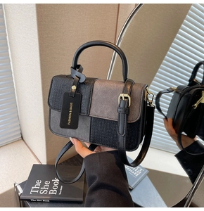 Detailaufnahme der zweifarbigen Tasche mit Webstruktur und goldenen Metallbeschlägen