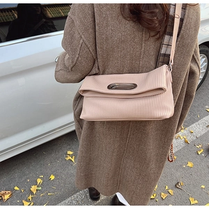 Detail view of pink pleated shoulder bag with metal oval handle and fine accordion texture