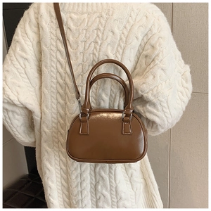 Detail of a brown glossy bowling bag with silver hardware and detachable strap