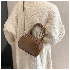 Brown glossy bowling bag styled with a white cable knit sweater for an autumn look