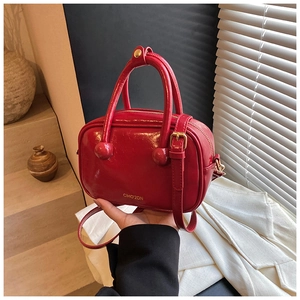 Dettaglio borsa Boston in vernice rossa con logo CIHO'2DN dorato e manici a sfera