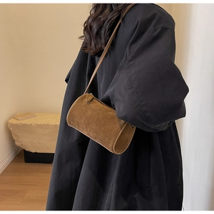 Brown suede cylindrical Boston bag shown worn crossbody over a classic black wool coat