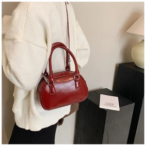 Close-up of a burgundy glossy leather handbag with silver hardware and dual top handles