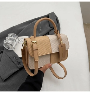 Detailaufnahme der zweifarbigen Handtasche mit Webstruktur und goldenen Metallteilen