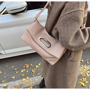 Detail of pleated shoulder bag with oval silver metal buckle shown in street style scene