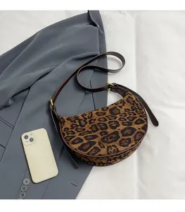 Leopard print crossbody bag size comparison with a smartphone on textured fabric