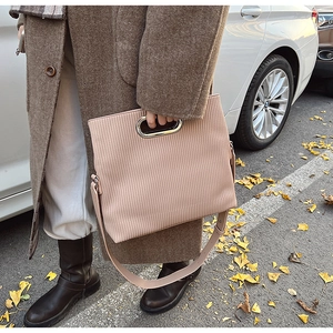 Pink corduroy crossbody bag featuring unique oval metal handle and street style design