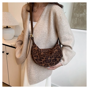 Detail of leopard print crescent crossbody bag with brown leather strap and gold buckle
