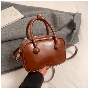 Dettaglio borsa a mano marrone vintage con logo dorato e doppi manici rotondi