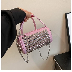 Detailed macro view of a pink cylinder bag featuring silver rhinestone studs and chain strap