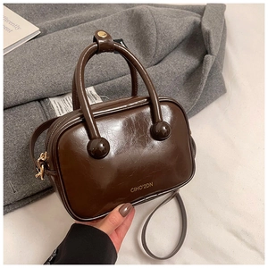 Dettaglio della borsa in pelle lucida marrone scuro con logo dorato e manici tondi