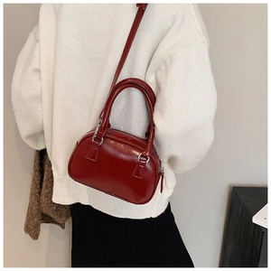 Close-up of a deep red glossy leather Boston style handbag with silver metal hardware