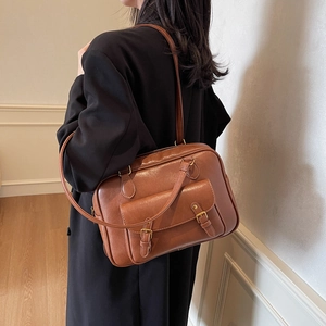 Mochila mensajera vintage de cuero marrón mostrada de lado llevada por una modelo