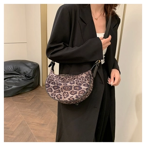 Close-up of leopard print crossbody bag with black leather strap and golden buckle details