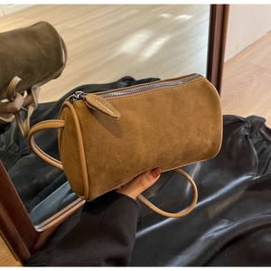 Close-up of brown suede barrel bag with smooth metal zipper and long leather puller
