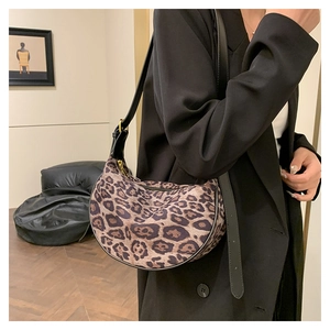 Leopard print crescent bag worn with black blazer showing crossbody strap detail