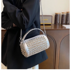 Detail view of silver rhinestone cylinder bag with metallic chain strap and hand grip