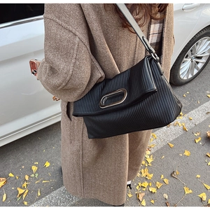 Detail of black pleated leather shoulder bag with silver metal buckle on a street